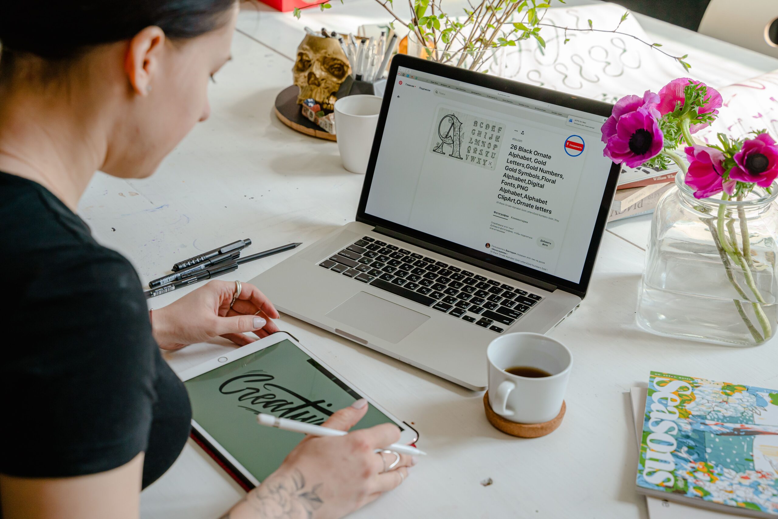 A woman works creatively with a tablet and laptop in a bright, colorful office space.